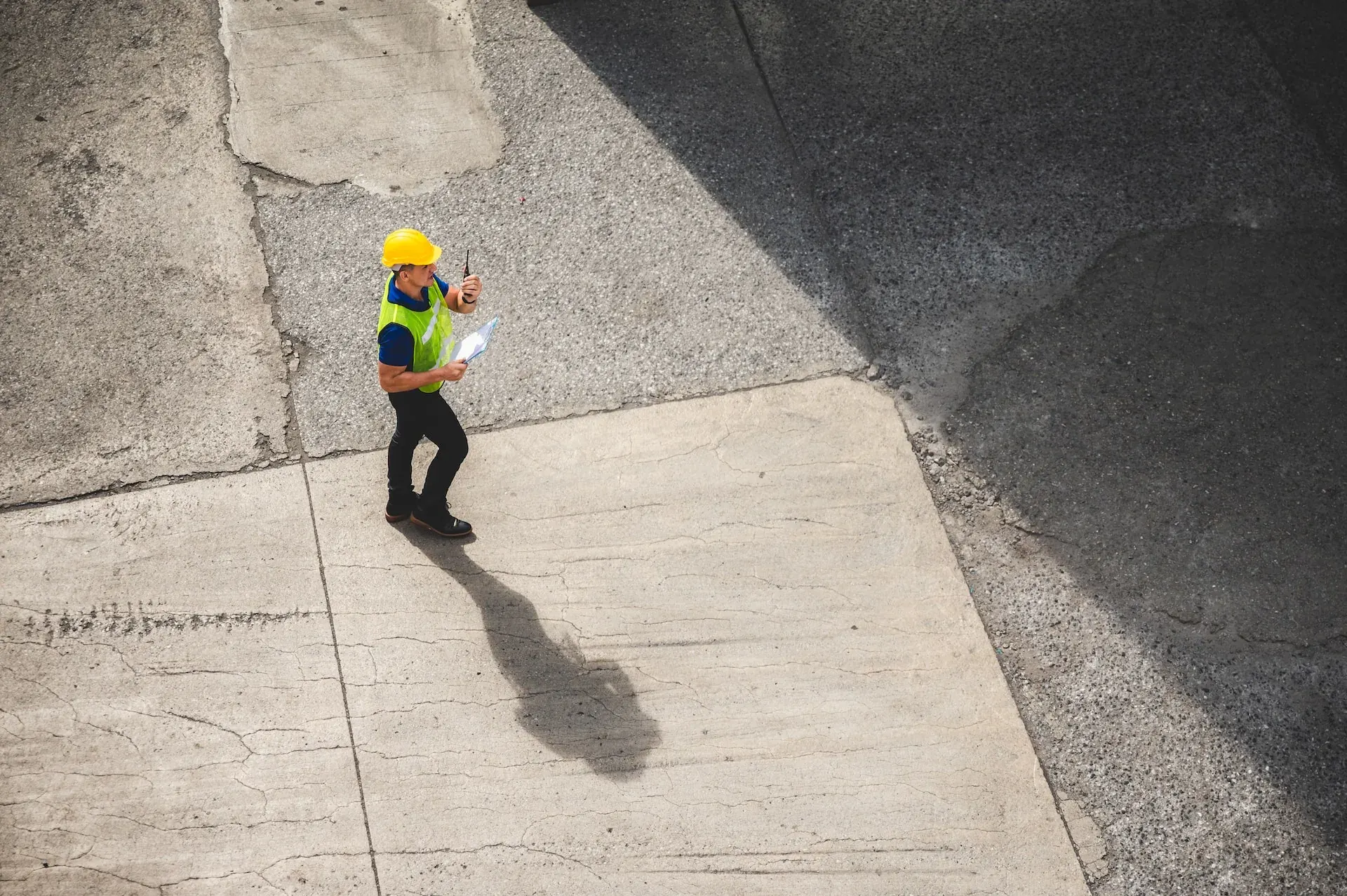 A site manager crossing an industrial yard at the start of a shift.